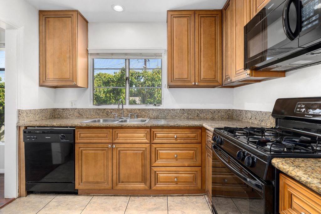 Van Nuys CA Apartments for Rent - Colonial Manor - Traditional Kitchen with Black Appliances, Sandy Countertops, Dark Tan Cabinetry, Window, and Overhead Lighting