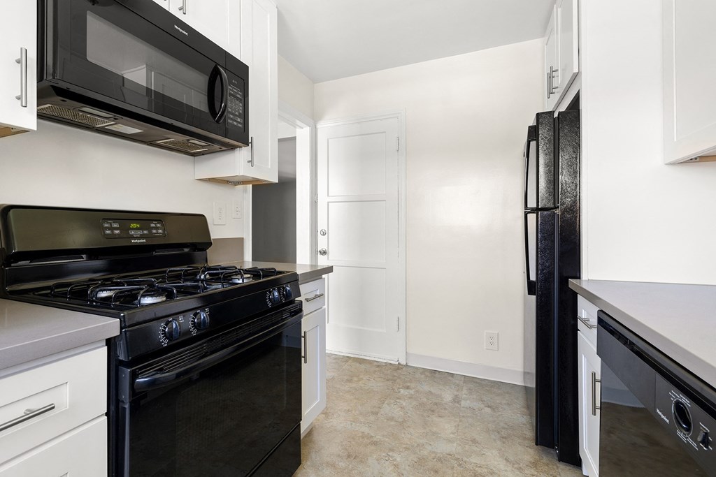 a renovated kitchen with black appliances and white cabinets and a black refrigerator