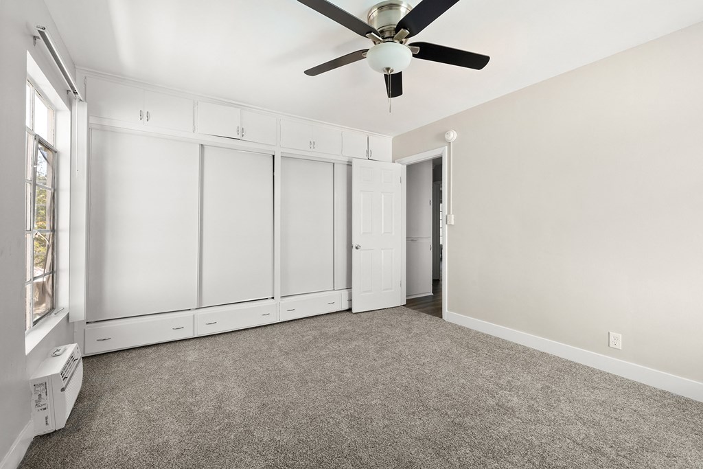 an empty room with white cabinets and a ceiling fan