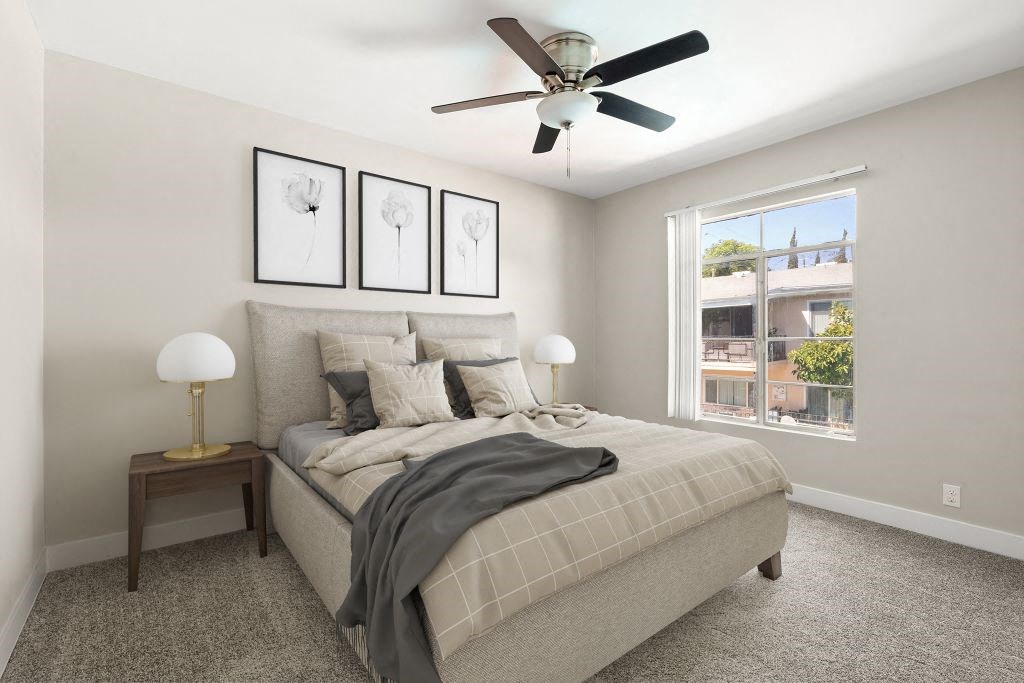 A bedroom with a bed, a ceiling fan, and two framed pictures on the wall.
