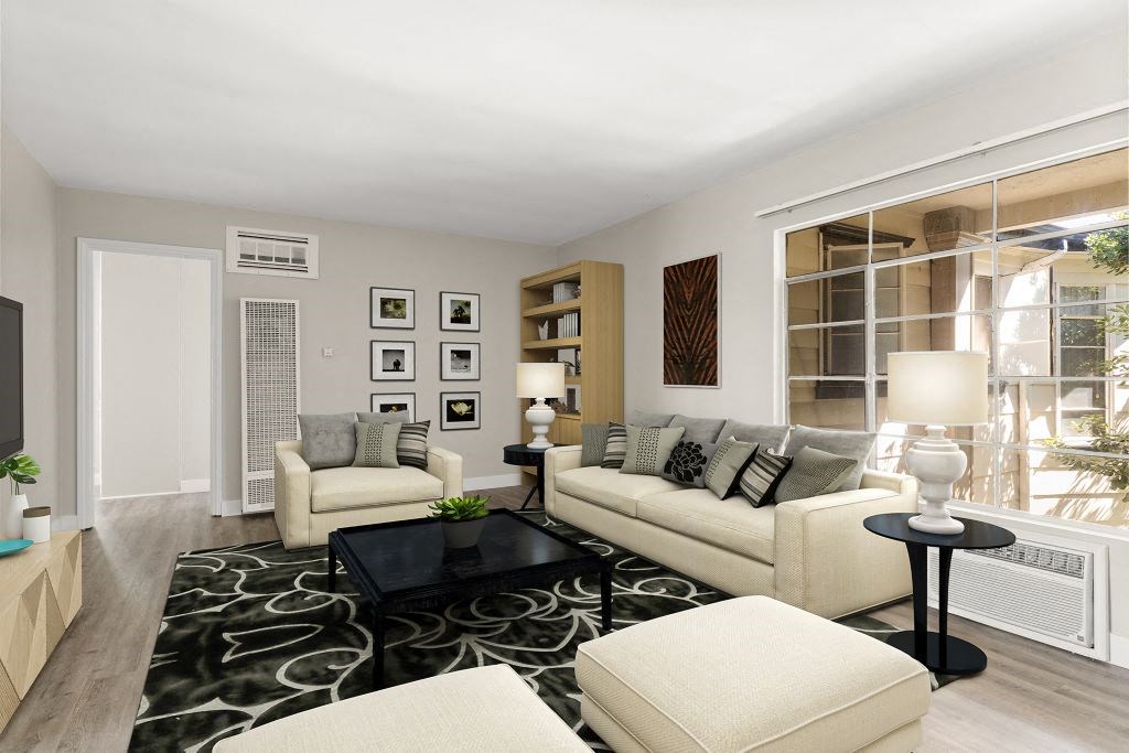 A modern living room with a black and white patterned rug, a white sofa, a black coffee table, and a large window with a view of the city.