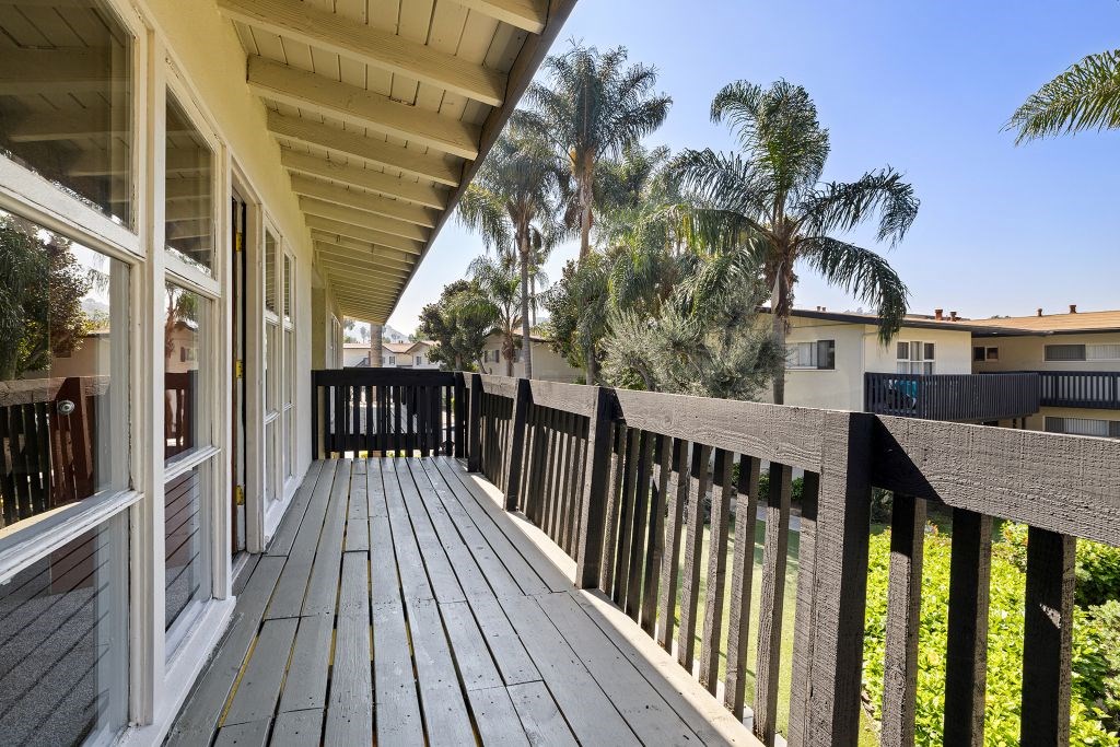 A wooden deck with a railing and a house in the background.