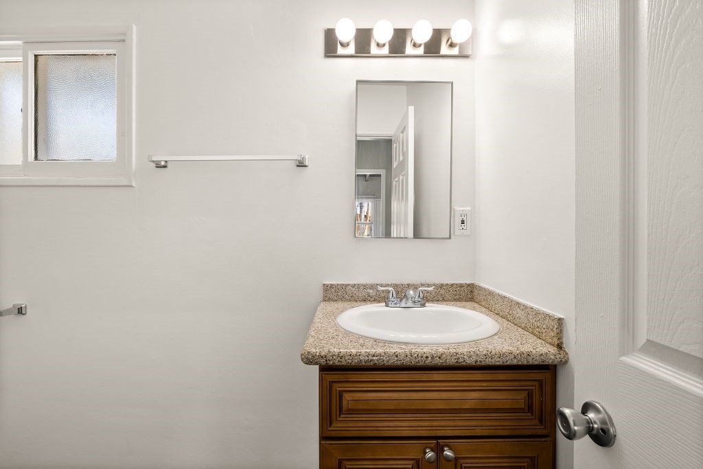 A bathroom with a sink, mirror, and wooden cabinet.