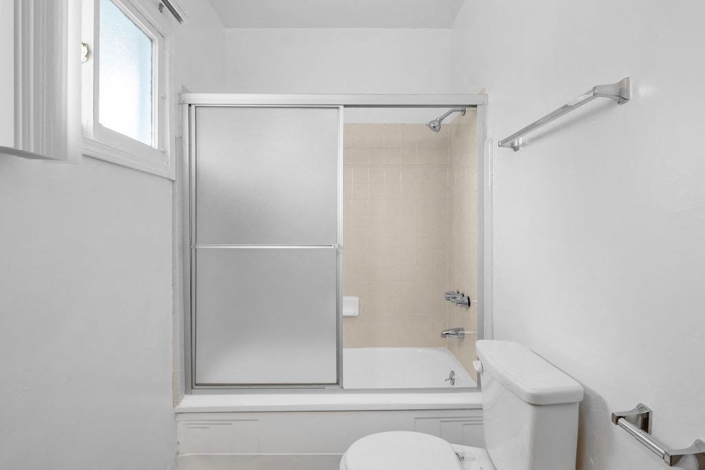 a white bathroom with a shower and a toilet