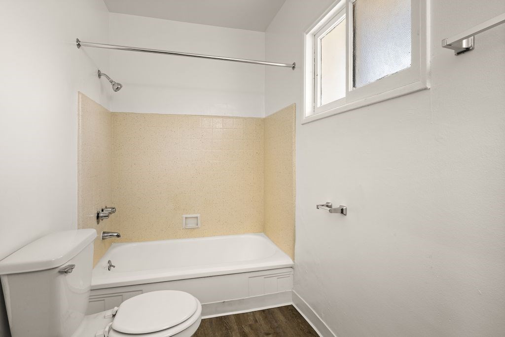 A white toilet sits next to a bathtub in a bathroom.