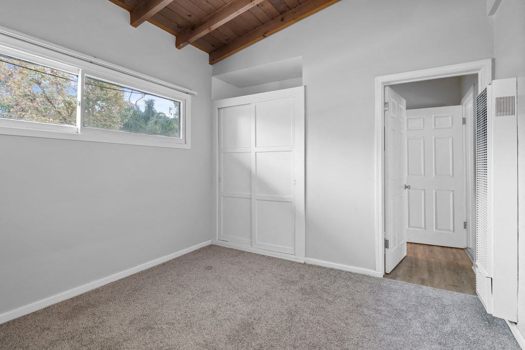 an empty bedroom with a closet and a window