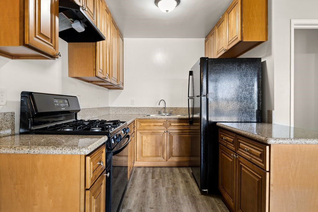 A kitchen with a black refrigerator and wooden cabinets.
