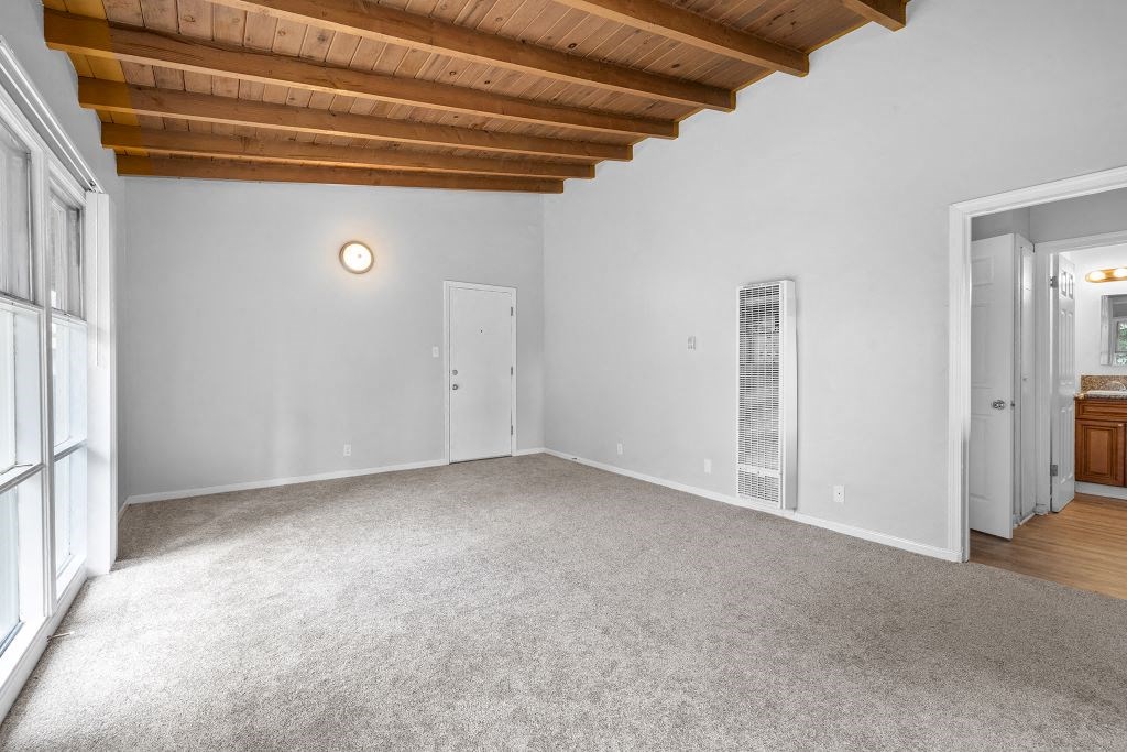 a living room with carpet and a door to a bathroom