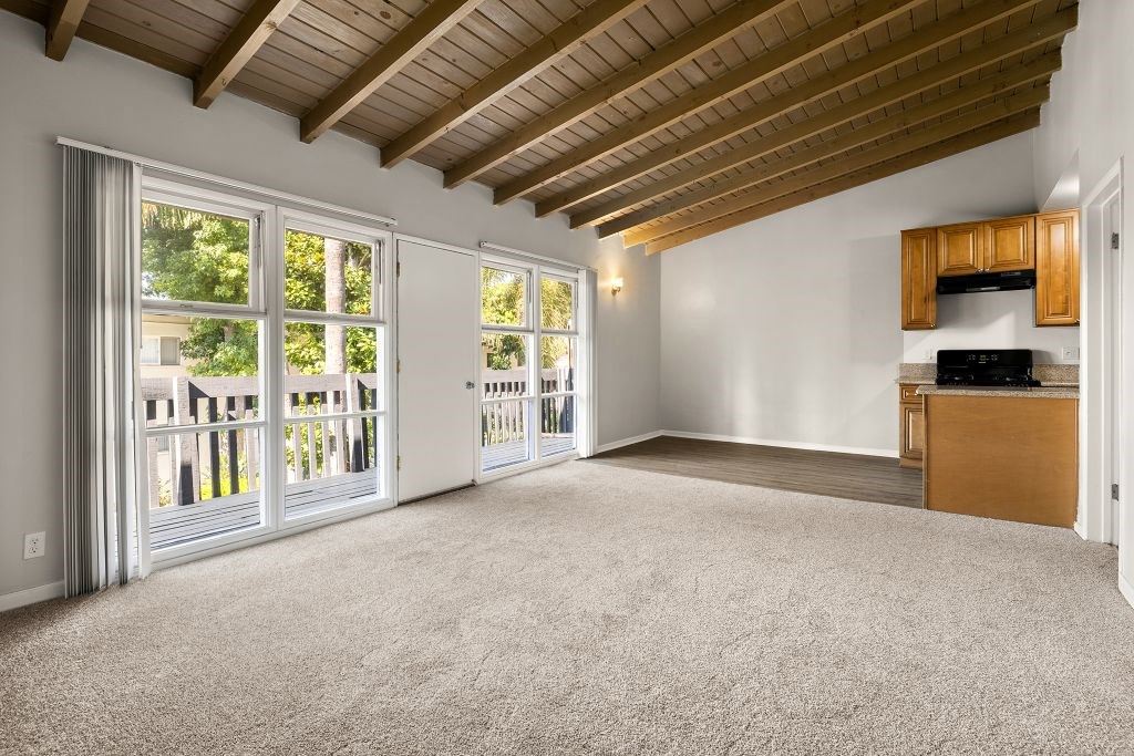 A spacious room with a wooden ceiling and carpeted floor.
