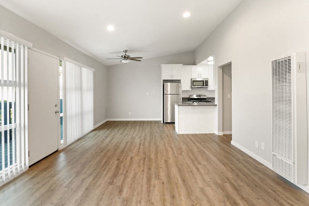 an empty living room and kitchen with wood flooring