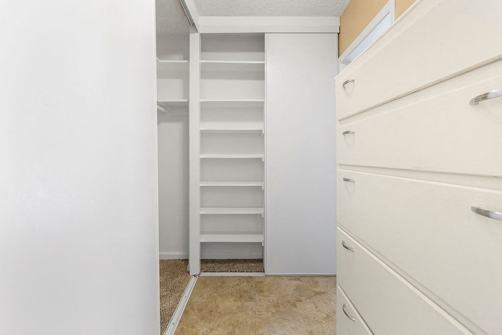 a walk in closet with white walls and a white dresser next to it