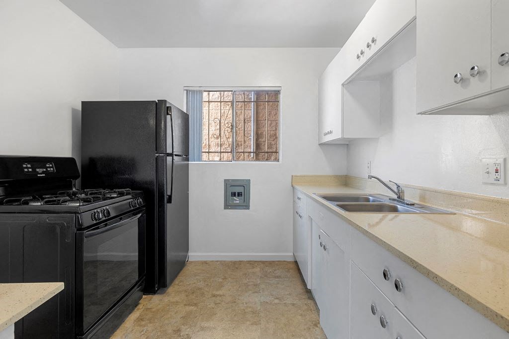 a kitchen with white cabinets and black appliances