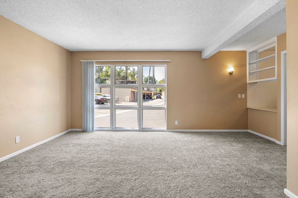 an empty living room with a sliding glass door and a bookshelf