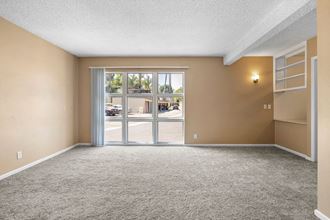 an empty living room with a sliding glass door and a bookshelf - Photo Gallery