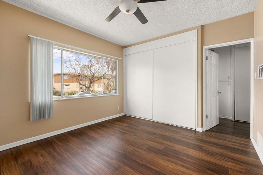 an empty bedroom with a large window and a ceiling fan