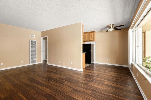 an empty living room with wood floors and a ceiling fan