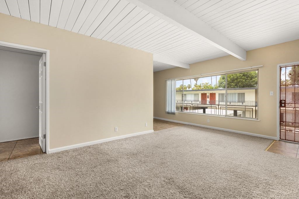 a bedroom with a large window and beige carpet