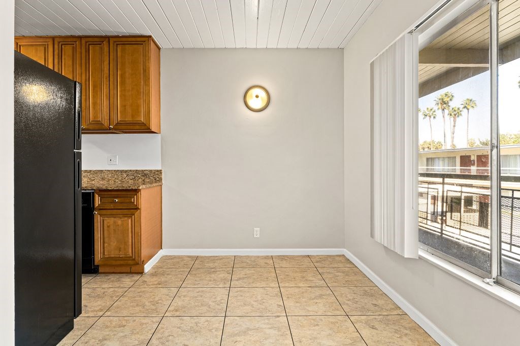 A kitchen with a black refrigerator and wooden cabinets.