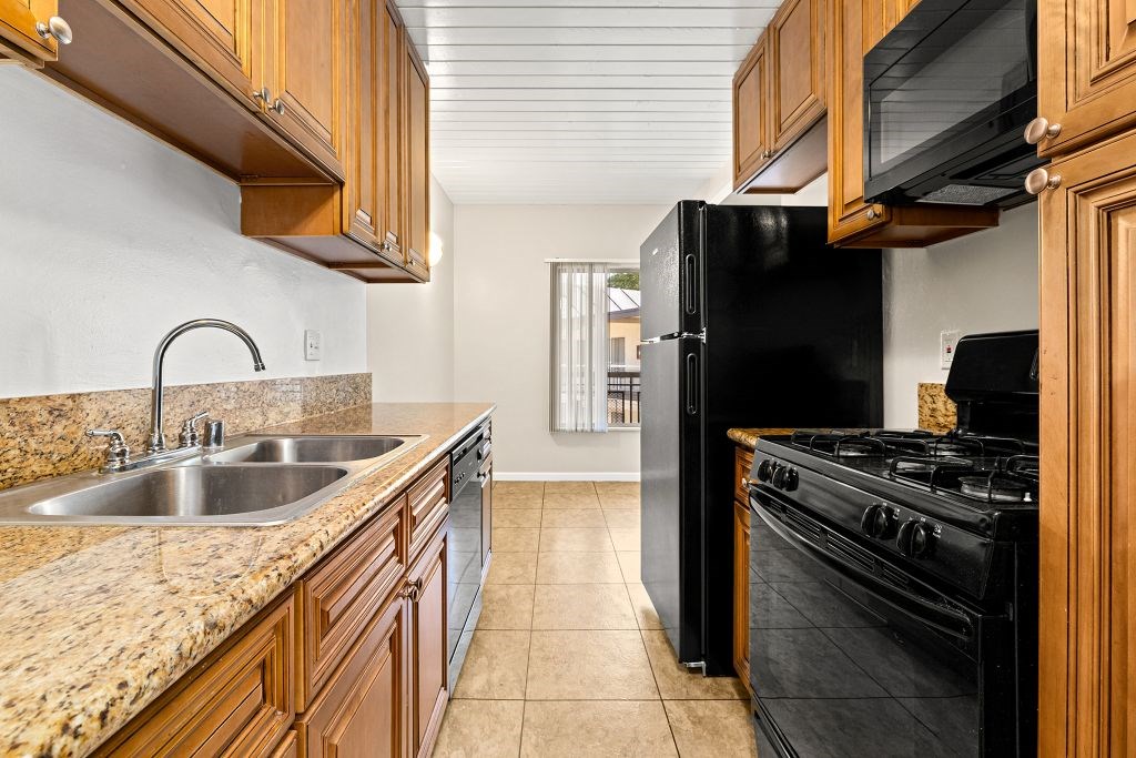 A kitchen with black appliances and wooden cabinets.