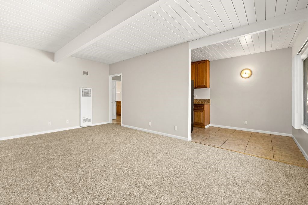 A room with a carpeted floor and a wooden door.