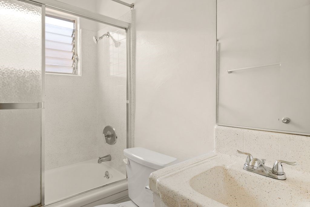 A white bathroom with a toilet, sink, and shower.