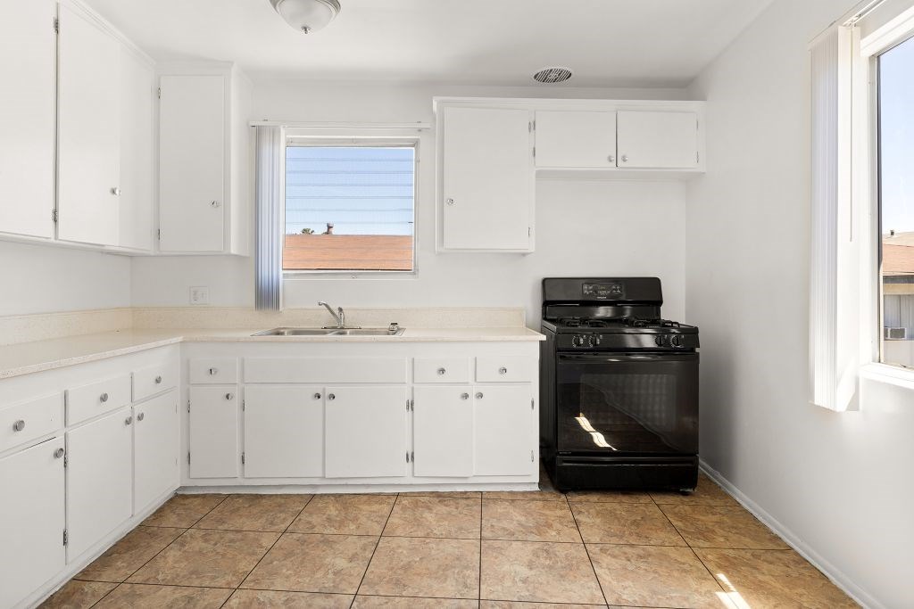 A kitchen with white cabinets and a black oven.