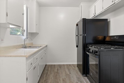 A kitchen with white cabinets and a black refrigerator.