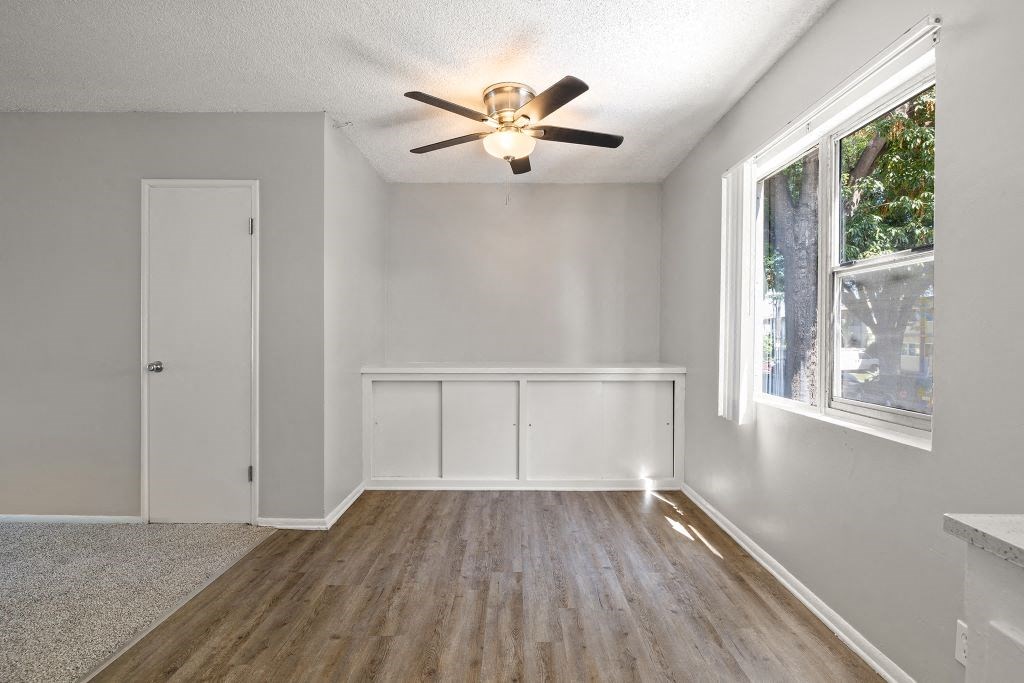 an empty room with a ceiling fan and a large window