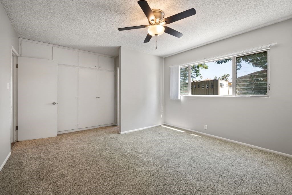 an empty bedroom with a ceiling fan