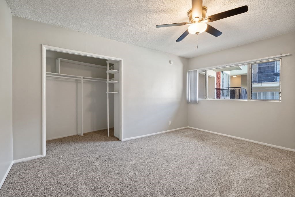 a bedroom with a ceiling fan and a mirrored closet