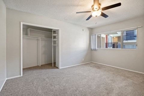 an empty bedroom with a ceiling fan and a closet