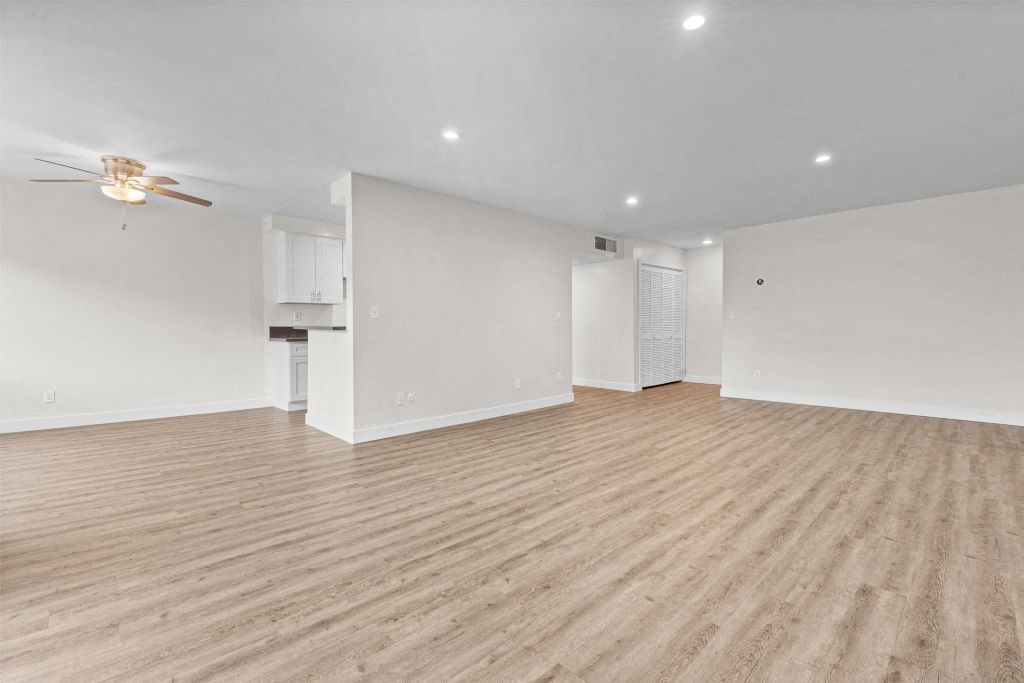 the living room and kitchen of an empty house with a ceiling fan