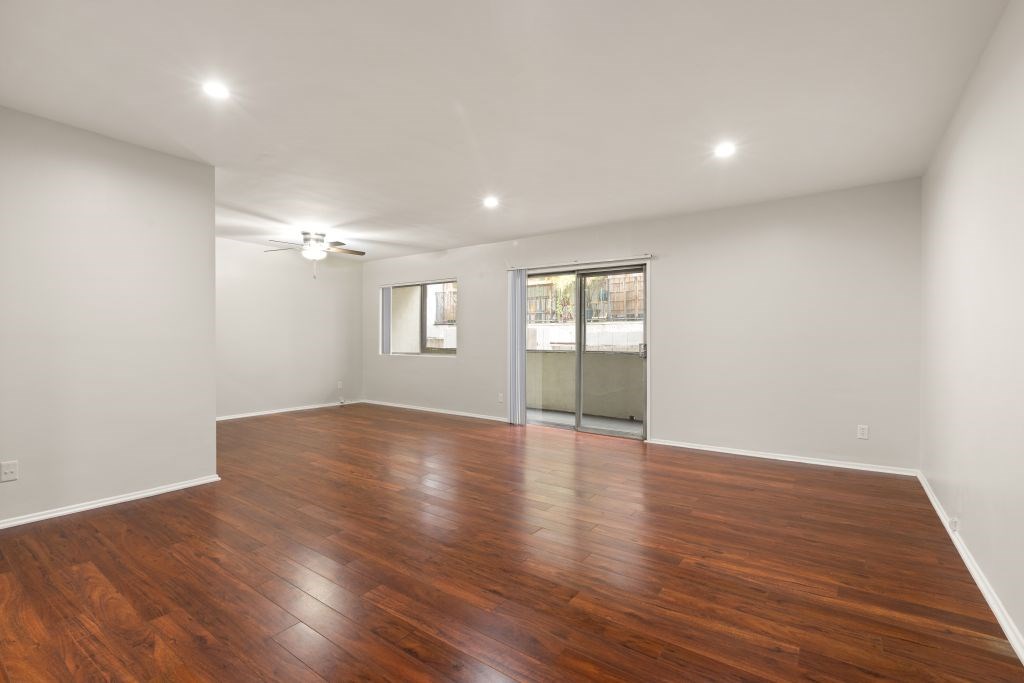 A room with wooden flooring and a sliding glass door.