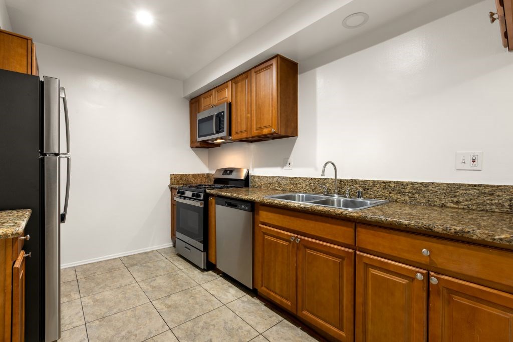 A kitchen with a black refrigerator and brown cabinets.