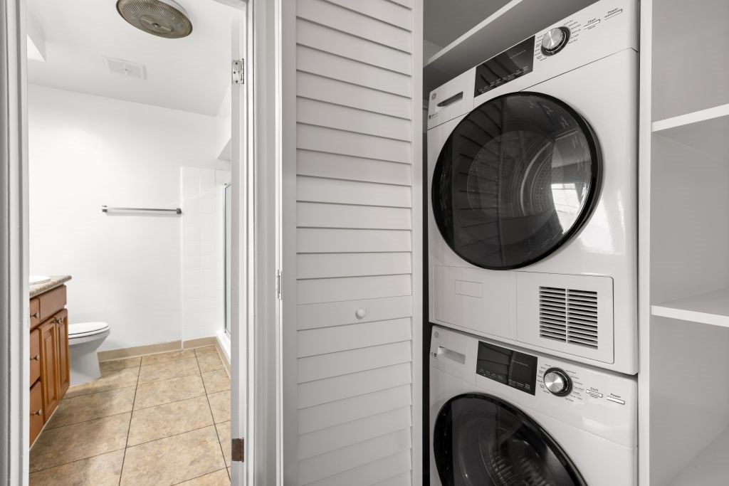 A white washing machine is in a small room with a toilet and a shower.