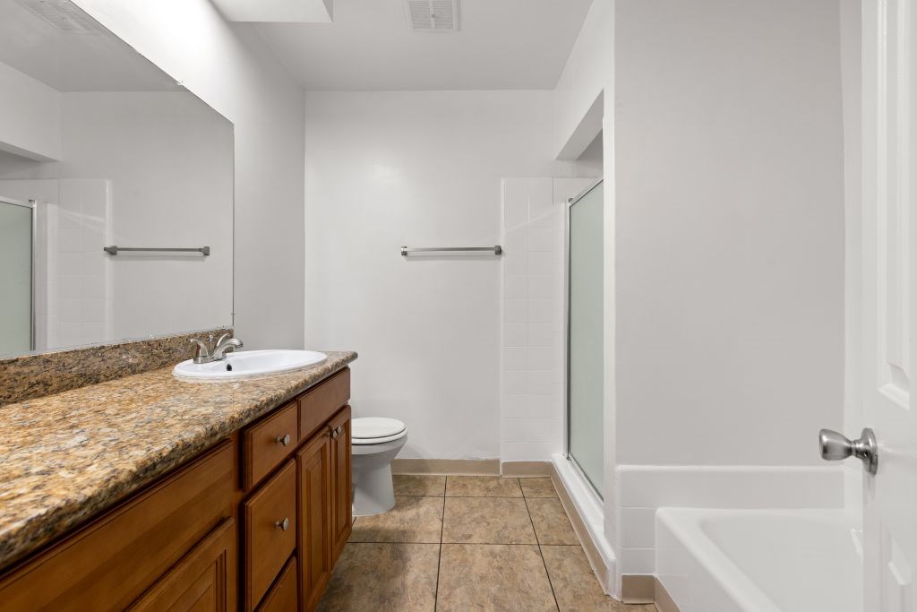 A bathroom with a marble countertop and a white bathtub.