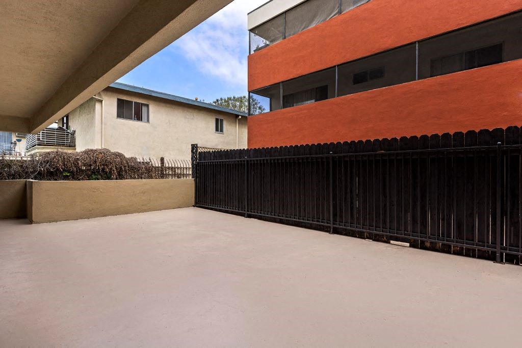 a view of the back of a building with a black fence and an orange building in the