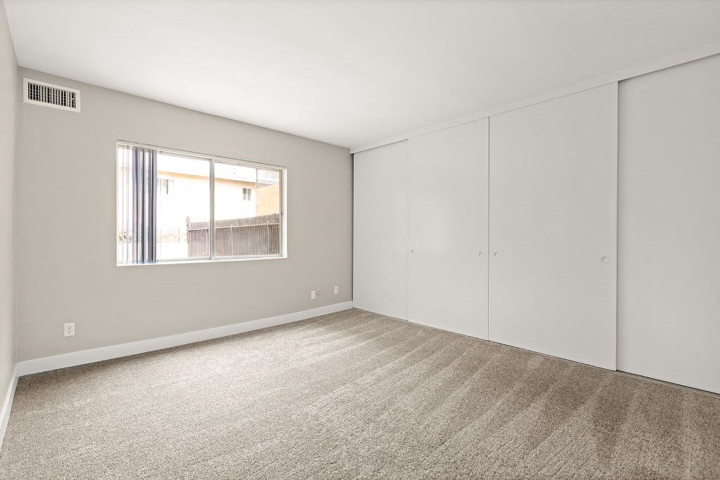 a bedroom with white walls and a window