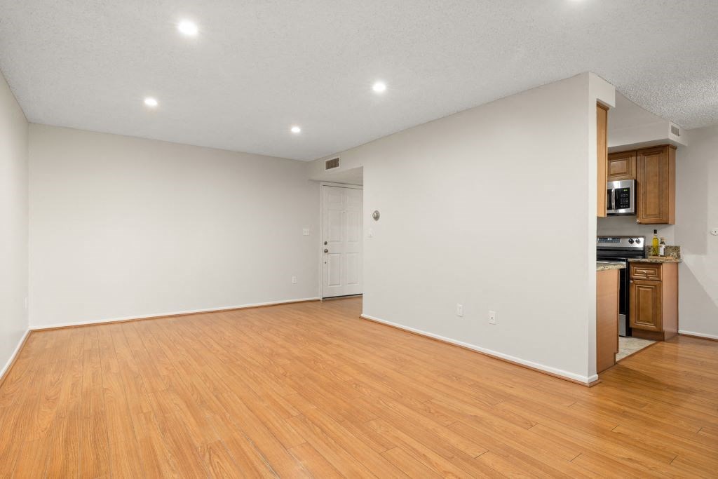 an empty living room with wood flooring and a kitchen at Lombardi Apartments, California, 91367