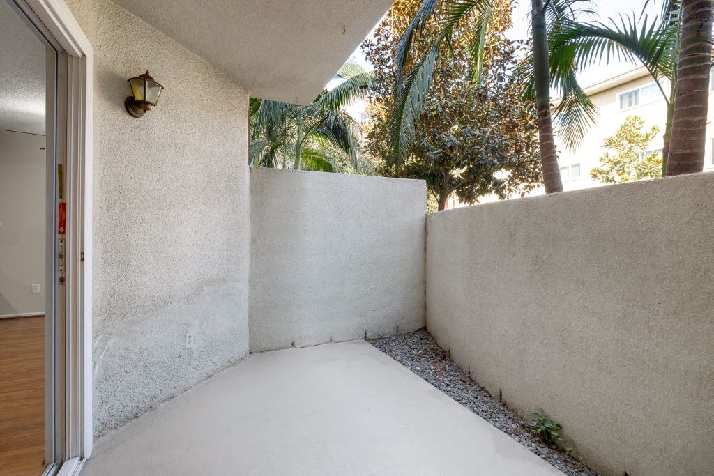 a patio with a wall and palm trees at Lombardi Apartments, Woodland Hills, 91367