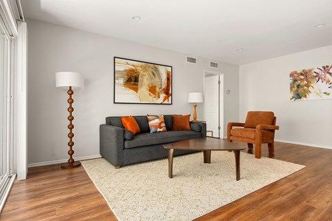 A living room with a grey couch, a brown chair, and a painting on the wall.