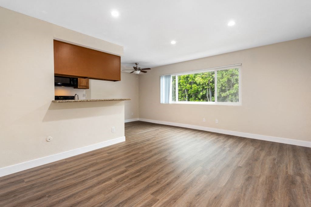 an empty living room with a large window and hardwood floors