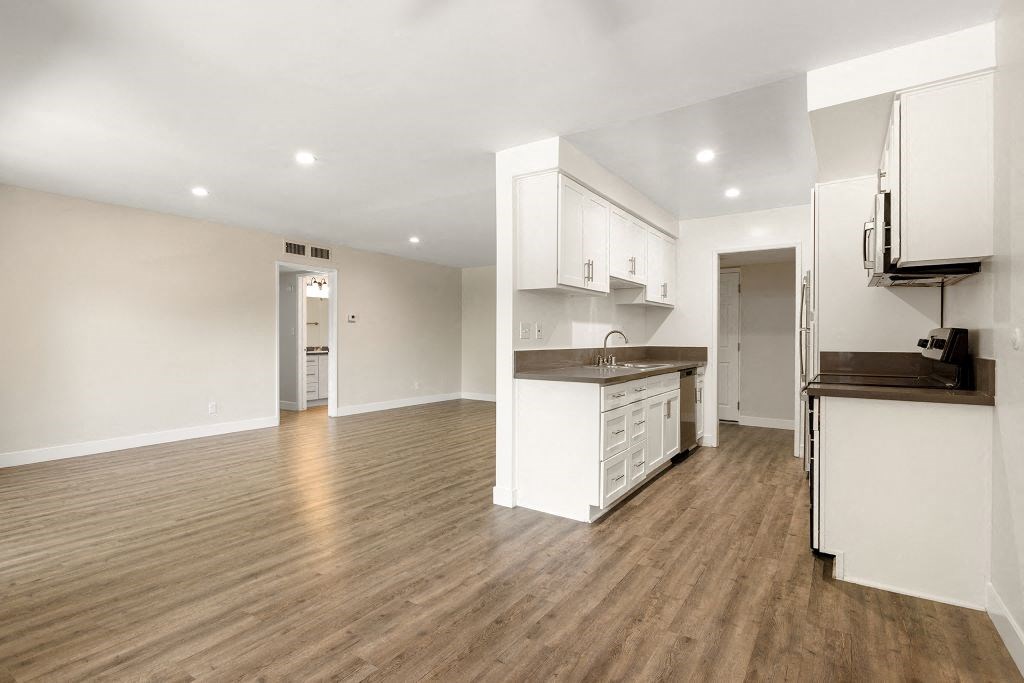 an empty living room and kitchen with a wood floor at Lombardi Apartments, Woodland Hills, California