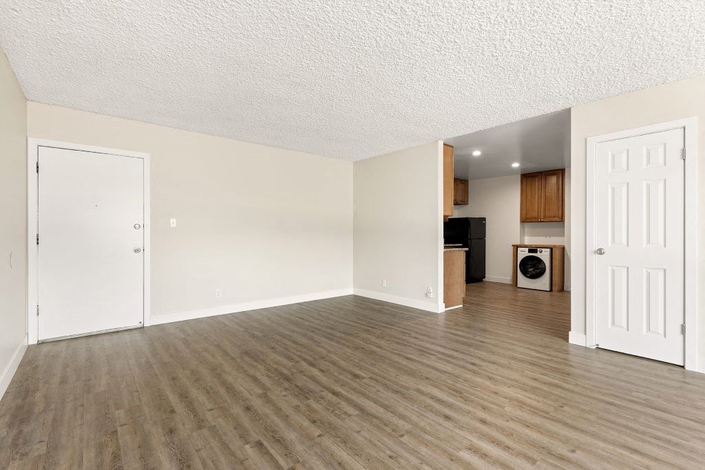 an empty living room and kitchen with wood flooring