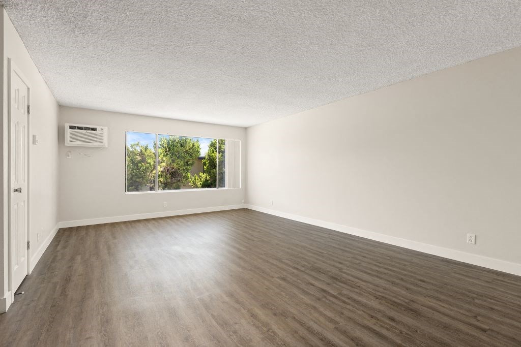 an empty living room with wood floors and a window