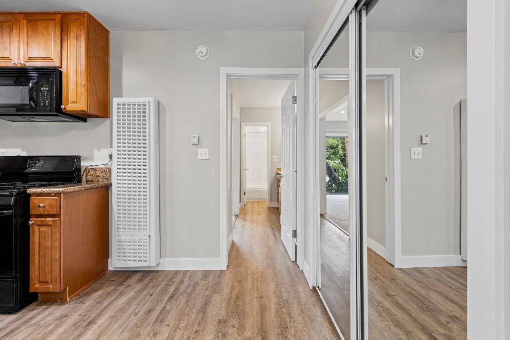 a kitchen with wood floors and white walls at Parkview Terrace Apartments, California