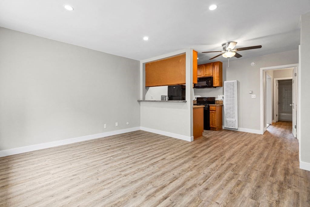 an empty living room with a kitchen in the background