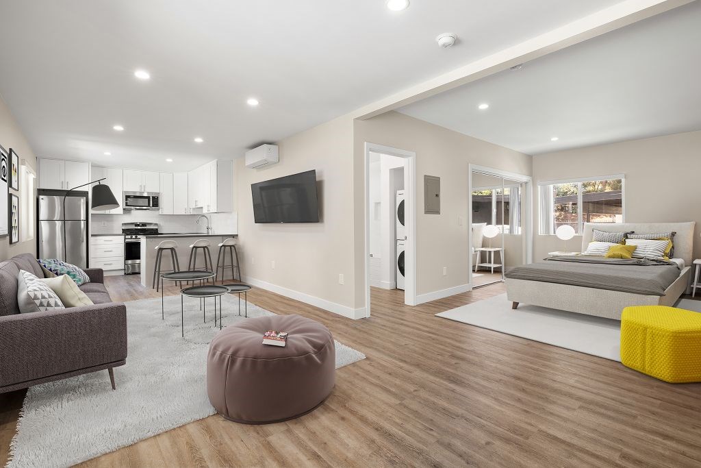 A modern living room with a grey couch, a brown ottoman, and a yellow stool.