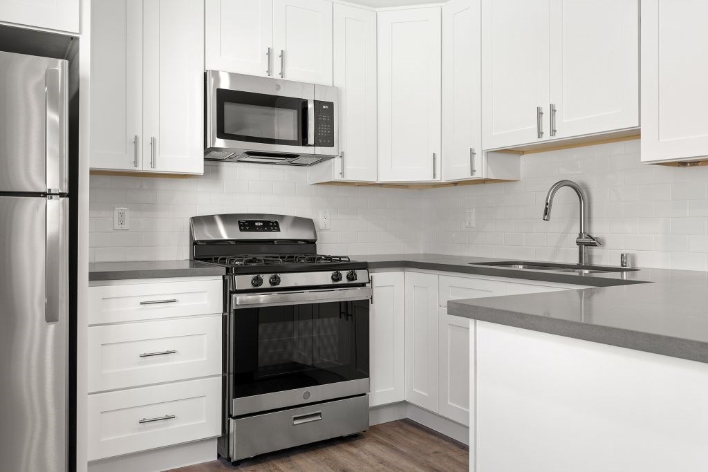A modern kitchen with a stainless steel refrigerator, oven, and microwave.