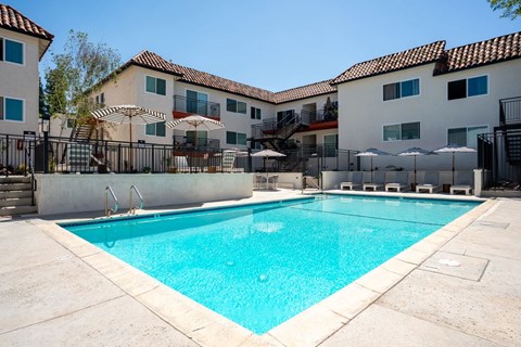 A swimming pool in front of a building with a black fence around it.